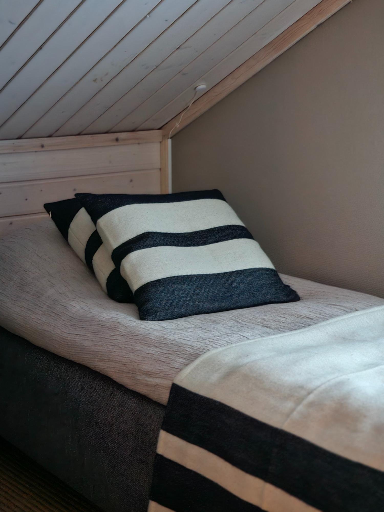 Yläkerran sänky ja raidalliset tekstiilit.